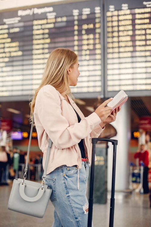 Girl in a airport. Blonde with a documents. Lady in a black t-shirt